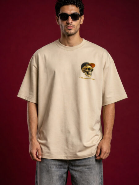 Man wearing oversized beige t-shirt with small skull graphic on chest, streetwear style, neutral background