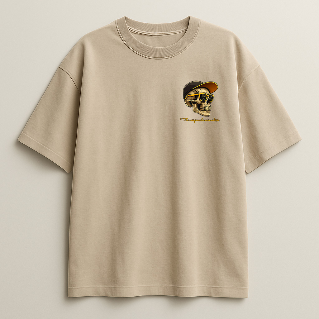 Close-up of the Minimalist Original skull graphic on a beige t-shirt, showing yellow sunglasses and black cap detail.