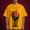 Male model wearing a mustard yellow oversized streetwear t-shirt featuring a large graphic of a black melting hand holding a realistic red heart. The chest includes elegant cursive typography and the garment is made from heavyweight cotton fleece with a boxy fit.