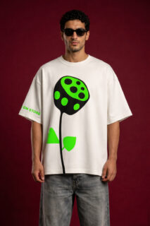 Man wearing oversized off-white t-shirt with neon green abstract flower graphic and black sunglasses against red background