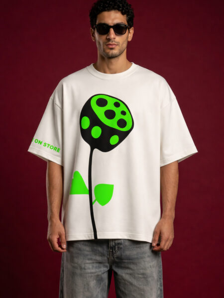 Man wearing oversized off-white t-shirt with neon green abstract flower graphic and black sunglasses against red background