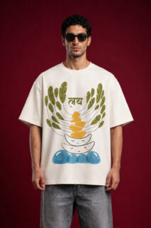 Front view of a man wearing a premium off-white oversized t-shirt featuring a "Laya" (लय) graphic with abstract balancing stones, green leaves, and blue water motifs.