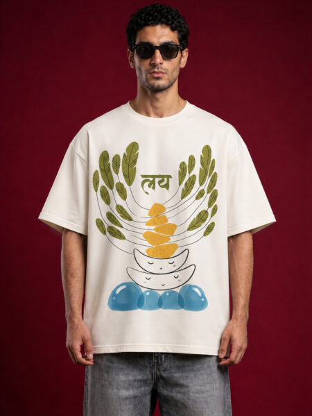 Front view of a man wearing a premium off-white oversized t-shirt featuring a "Laya" (लय) graphic with abstract balancing stones, green leaves, and blue water motifs.