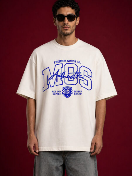 A man wearing an oversized off-white streetwear t-shirt with a bold blue "MOS" graphic on the chest. The design includes "Authentic" in script and a "2026" shield emblem. He is wearing black sunglasses and grey washed denim, standing against a dark maroon textured background