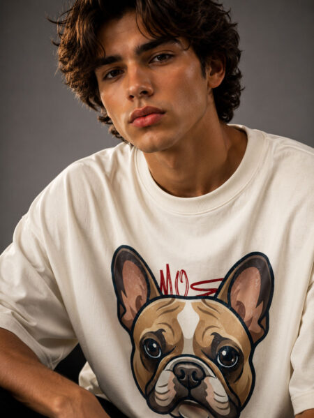 Close-up shot of a male model in a relaxed-fit cream graphic tee showcasing the detailed artwork of a French Bulldog with a red accent