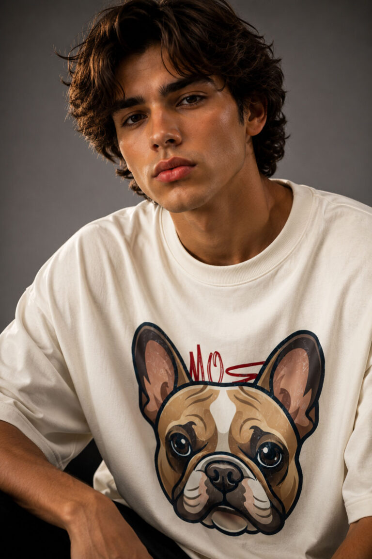 Close-up shot of a male model in a relaxed-fit cream graphic tee showcasing the detailed artwork of a French Bulldog with a red accent