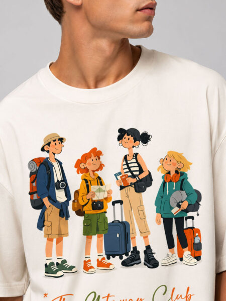 Close-up of the high-definition direct-to-garment print on a cream t-shirt, showing detailed cartoon characters holding luggage with "The Getaway Club" text below.