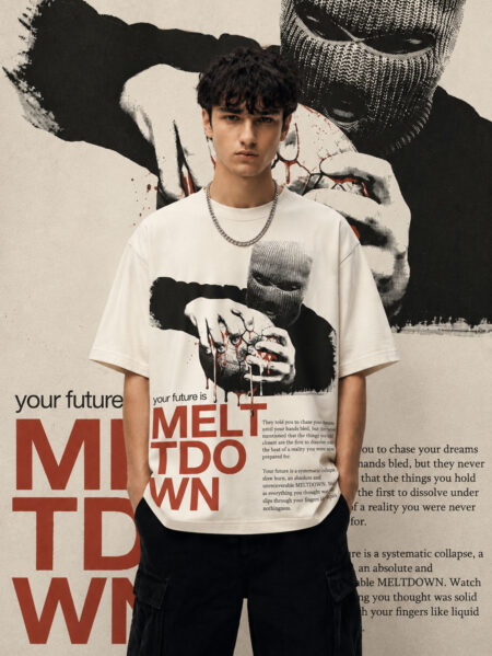 A model wearing an off-white, heavyweight cotton oversized t-shirt featuring a dark, industrial-style graphic of a figure in a balaclava holding a globe, with the text "MELTDOWN" in bold red lettering